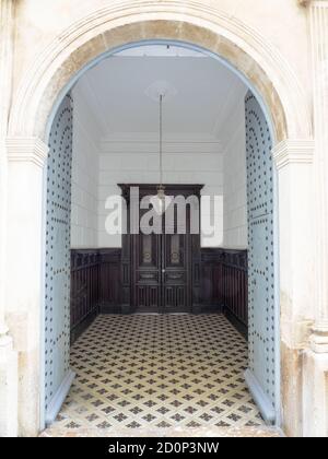 Ingresso ornato ad arco con porta rustica in legno con borchie in metallo e piastrelle di ceramica dipinte a mano chiamato azulejo Foto Stock
