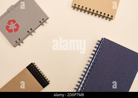 notebook ecologici per ufficio con vista dall'alto, con spazio per la copia in carta riciclata su sfondo pastello. simbolo di riciclaggio sulla copertina Foto Stock