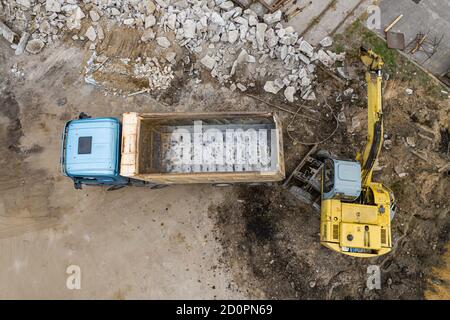 l'escavatore carica sabbia nella vista dall'alto di un camion. Foto Stock