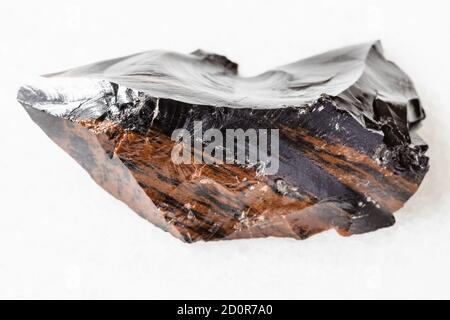 macrofotografia di un campione di minerale naturale da collezione geologica - mogano non lucidato Obsidian (vetro vulcanico) Dall'Armenia su marmo bianco Foto Stock