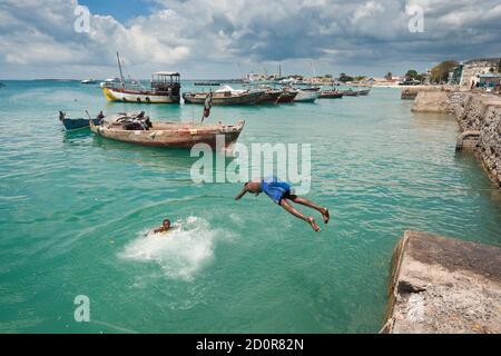 Stone Town, Zanzibar, Tanzania | 21 ottobre 2007: Gli adolescenti saltano nel mare turchese del porto Foto Stock