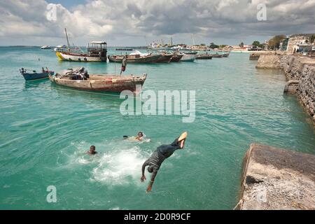 Stone Town, Zanzibar, Tanzania | 21 ottobre 2007: Gli adolescenti saltano nel mare turchese del porto Foto Stock