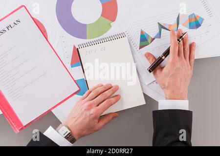 Uomo d'affari lavora con grafici a grafico sul tavolo. Foto Stock