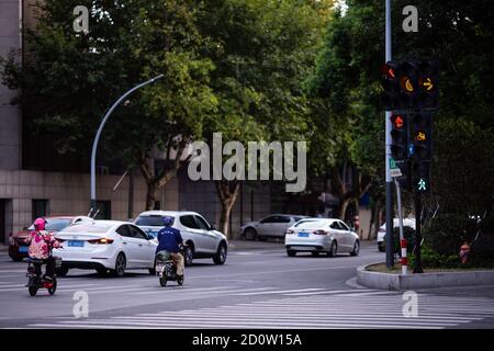 Huzhou, Cina 2020 settembre 28: Scooter elettrici e auto rush ore strada della città. Auto su strada in ingorgo su pedone Foto Stock