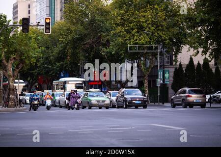 Huzhou, Cina 2020 settembre 28: Scooter elettrici e auto rush ore strada della città. Auto su strada in ingorgo su pedone Foto Stock