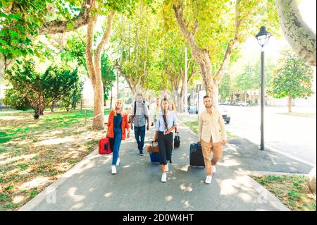 Gruppo di amici multirazziali che camminano nel parco cittadino vicino alla stazione ferroviaria - giovani all'aperto - nuovo concetto di stile di vita normale, con i giovani coperti Foto Stock