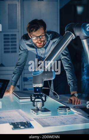 Vertical Shot of a Mechanical Engineer lavora con il futuristico braccio robotico e lo programma per oggetti metallici in movimento. High Tech Research Laboratory con Foto Stock