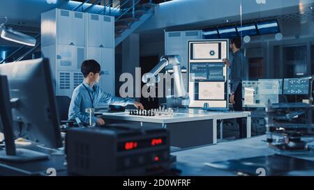 L'ingegnere giapponese professionista sta testando un'interfaccia di intelligenza artificiale giocando a scacchi con un braccio robotico futuristico. Sono dentro Foto Stock
