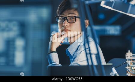 Ritratto di un serio professionista giapponese di sviluppo che pensa a. Il suo posto di lavoro in un laboratorio di ricerca High Tech con Computer moderno Foto Stock