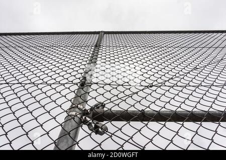 Immagine in scala di grigi ad angolo basso di una recinzione metallica cablata sotto un cielo limpido Foto Stock