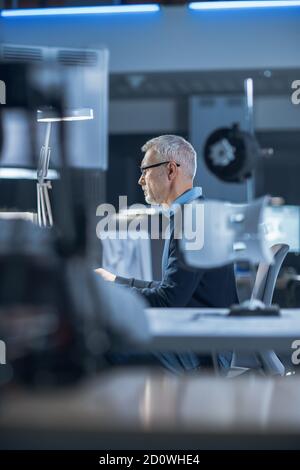 Foto di ingegnere industriale che lavora nel Centro di sviluppo di laboratorio di Ricerca, usando il computer. Sta lavorando alla progettazione di concept di New Efficient Engine. Foto Stock