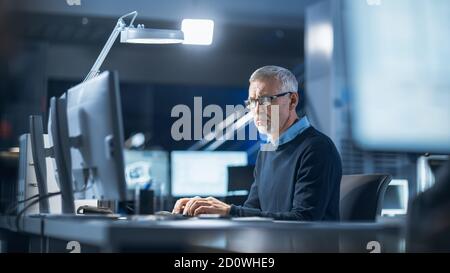 Foto di ingegnere industriale che lavora nel Centro di sviluppo di laboratorio di Ricerca, usando il computer. Sta lavorando alla progettazione di concept di New Efficient Engine. Foto Stock