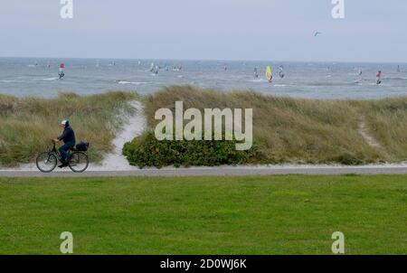 Heidkate, Germania. 03 ottobre 2020. Un ciclista corre lungo una diga nel Mar Baltico, su cui scivolano i surfisti del vento. Credit: Frank Molter/dpa/Alamy Live News Foto Stock