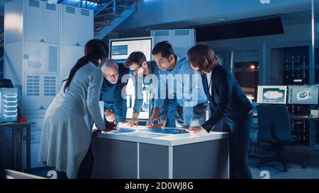 Incontri di ingegneri nel laboratorio di Ricerca tecnologica: Ingegneri, scienziati e sviluppatori si sono riuniti intorno illuminato tavolo da conferenza, parlare e. Foto Stock