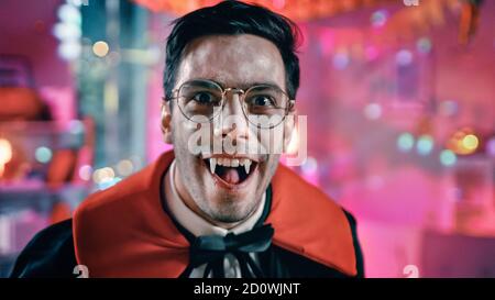 Halloween Costume Party: Ritratto del conte Dracula sorridente creeply, mostra i suoi sanguinosi fangs mortali. In background decorata tematicamente Camera con Foto Stock