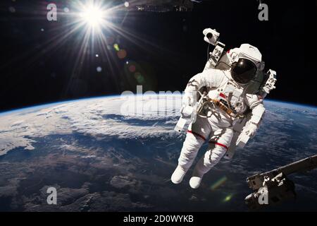 Astronauta che cammina nello spazio con sfondo terrestre. Elementi di questa immagine forniti dalla NASA. Foto Stock