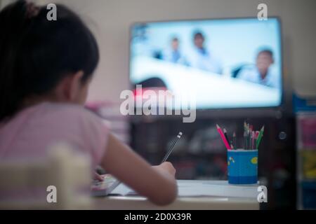 Studentessa bambina bambina che impara in TV a casa, distanza sociale durante la quarantena, concetto di educazione online Foto Stock