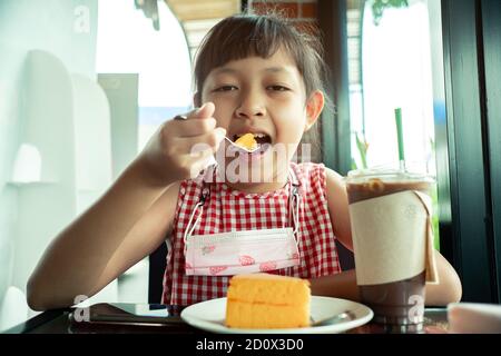 Bambina asiatica che mangia torta chiffon Foto Stock