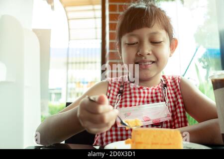 Bambina asiatica che mangia torta chiffon Foto Stock