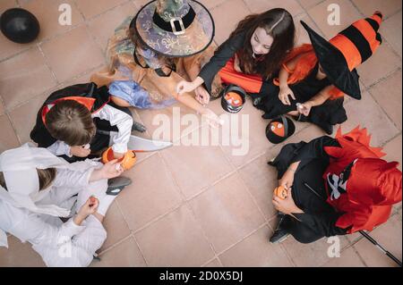 I bambini che condividono e confrontano le loro caramelle su Halloween seduto sopra un piano Foto Stock