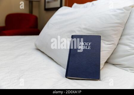 Bibbia blu sul letto in camera d'albergo Foto Stock