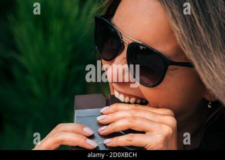 Donna carina stanca di stress da dieta e molto felice di mangiare cioccolato. Mordere il cioccolato fondente. Foto Stock