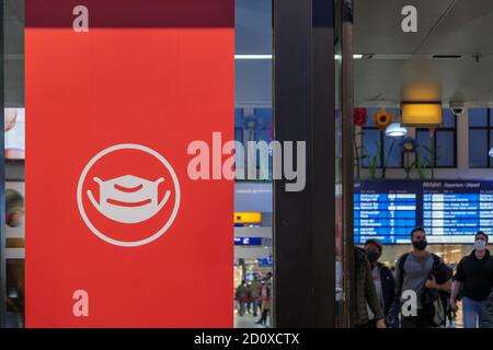 Messa a fuoco selezionata al simbolo della maschera protettiva bianca, segno rosso sul vetro della finestra all'ingresso della stazione ferroviaria durante la distanza sociale da epid Foto Stock