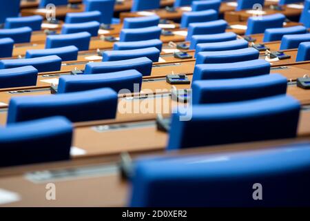 All'interno di una sala del parlamento vuota. Sedie blu in linea con le macchine di voto per ogni posto sulla scrivania. Foto Stock