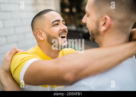 Ritratto di felice coppia gay di trascorrere del tempo insieme e abbracciando in strada. Lgbt e il concetto di amore. Foto Stock