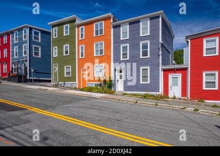 Una fila di case colorate in legno nel centro di St John, Terranova. Gli edifici annessi hanno pannelli laterali, doppie finestre appese e tetti piani Foto Stock