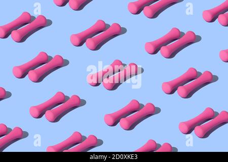 Modello sportivo concettuale con manubri rosa su sfondo blu. Foto Stock