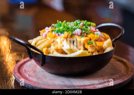 Chip fritti sul recipiente del ferro. Cipolla verde e pancetta. Foto Stock