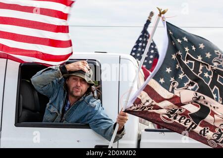 Il partecipante alla Trump Parade svonda la bandiera fuori dalla finestra sulla i-270 mentre si tiene sul suo cappello. I sostenitori di Trump si sono mostrati in gran numero sulla i-270 in un evento chiamato Trump Parade. Durante questo evento, i sostenitori di Trump hanno guidato la i-270, l’autostrada che circonda Columbus, Ohio, dalle 10:00 a mezzogiorno per mostrare il sostegno al presidente Donald Trump durante la stagione elettorale. I partecipanti alla Trump Parade hanno guidato nel vicolo centrale dell'autostrada, e sono stati accolti con il sostegno dei cavalcavia e dei compagni di guida. L'evento ha ricevuto un'opposizione minima. Foto Stock