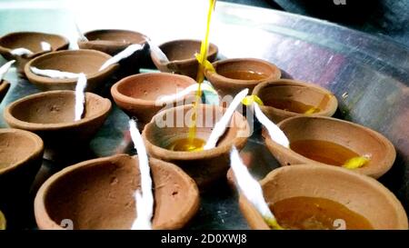 Un uomo che aiuta durante il mettere olio in candele di argilla Foto Stock