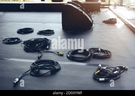 In preparazione di un concerto, i cavi audio e gli altoparlanti sono sul podio del palco. Concetto di evento Foto Stock