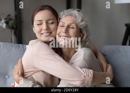 Primo piano sorridente donna matura e figlia adulta abbracciando Foto Stock