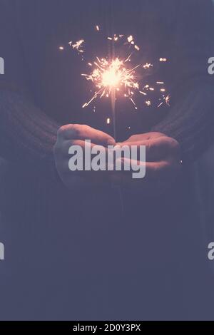 Celebrazione e speranza concetto futuro con primo piano di coppia di mani con sparkler sparato nel buio del notte intorno - capodanno e festa Foto Stock