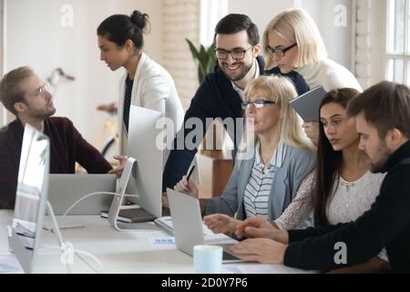 Diversi dipendenti collaborano utilizzando il computer in ufficio Foto Stock