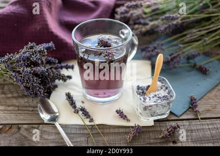 tè fresco alla lavanda con zucchero di lavanda in una tazza di vetro. Lavanda (Lavandula angustifolia), ha un effetto calmante e antispasmodico. Foto Stock