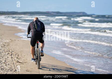 Ciclisti sulla spiaggia deserta di Swinoujscie sul polacco Costa del Mar Baltico Foto Stock