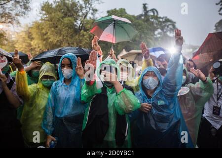 Durante una protesta davanti al Ministero dell'Istruzione, i dimostranti degli studenti delle scuole superiori in impermeabile hanno visto sollevare le mani mostrando il segno a tre dita. Gli attivisti degli studenti hanno organizzato una protesta mobile verso cinque scuole superiori della capitale tailandese chiedendo riforme dell’istruzione, regole scolastiche meno severe, la fine degli abusi sui bambini degli asili, più tolleranza e rispetto. Gli studenti chiedevano anche le dimissioni del ministro dell'Istruzione Nataphol Teepsuwan. Foto Stock