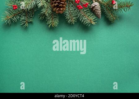 Composizione di Natale. Decorazioni natalizie, coni di pino, rami di abete su sfondo verde. Disposizione piatta, vista dall'alto, spazio per la copia. Foto Stock