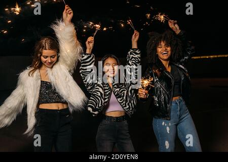 Gruppo multietnico di giovani amici femminili che si divertono a tenere sparklers Foto Stock