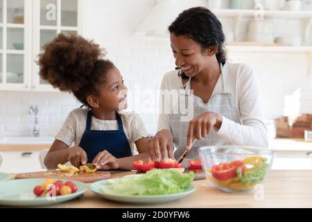 Felice afro ragazza cucina con mamma in cucina. Foto Stock