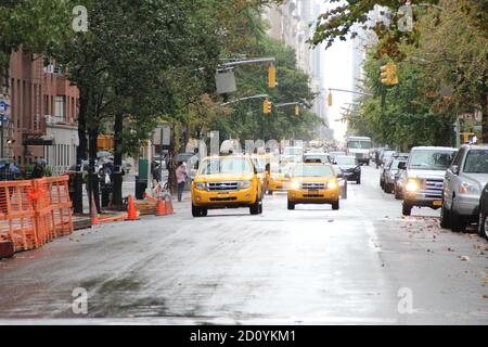 taxi gialli che guidano in città su un bagnato strada Foto Stock