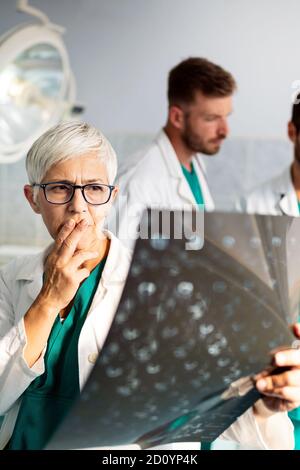 Gruppo di medici che esaminano una radiografia in ospedale per fare diagnosi Foto Stock