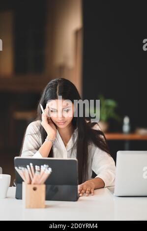 Una bella donna sta usando un tablet per computer alla scrivania bianca. Foto Stock