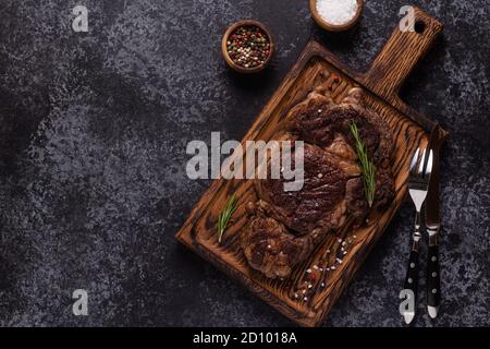 Bistecca di manzo alla griglia con spezie su tavola di legno, vista dall'alto. Foto Stock
