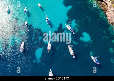 La foto del 28 luglio 2020 mostra le barche ormeggiate nel Mar Mediterraneo nella baia di Portinatx a Ibiza, parte delle Isole Baleari spagnole, che è popolare tra le famiglie britanniche, ma è ora una zona no go per i turisti britannici. Le barche sono normalmente utilizzate per escursioni giornaliere, ma il la mancanza di turisti significa che sono licenziati per il momento. Foto Stock