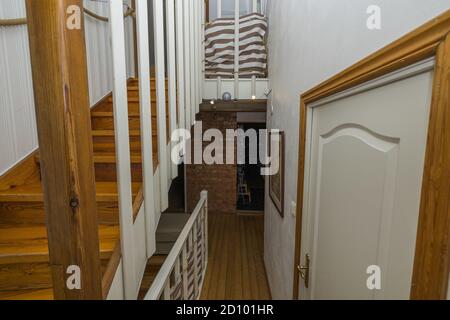 Bella vista interna del corridoio con scale di legno con ringhiere bianche e porte bianche. Foto Stock